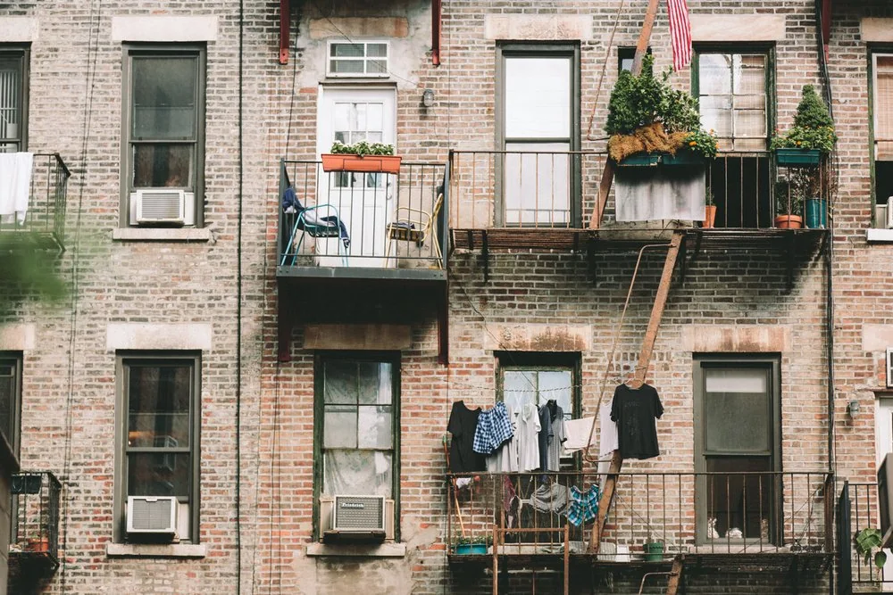 Brick apartment building with fire escapes and window plants